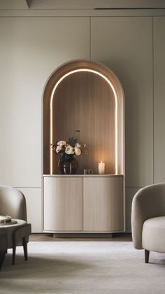 a living room with two chairs and a vase filled with flowers on top of a cabinet