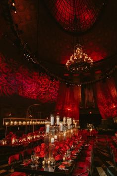 an elaborately decorated dining room with red lighting and chandeliers on the ceiling