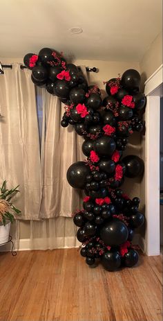 black and red balloons are arranged in the shape of a heart on a wooden floor