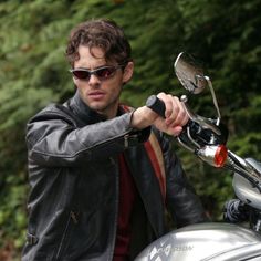 a man in black jacket and sunglasses on a motorcycle