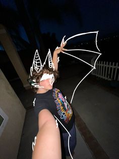 a person with their hand up in the air while wearing a bat t - shirt