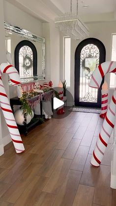 two giant candy canes are in front of the entry door to a home decorated for christmas