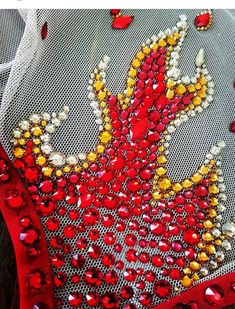 red and yellow sequins on white mesh with beads in the shape of a peacock