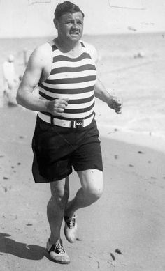 a man running on the beach in shorts and a tank top, with his mouth open