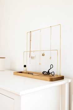 a pair of scissors sits on top of a white desk next to a jewelry holder