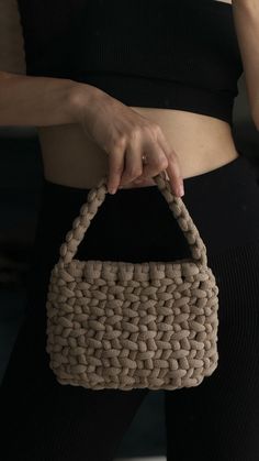 a woman holding a woven purse in her hand