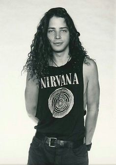 a black and white photo of a man with long curly hair wearing a nirvana t - shirt