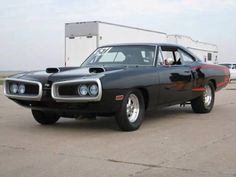 a black muscle car parked on top of a parking lot next to a white building