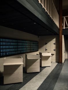 an empty room with several wooden benches in front of the wall and stairs leading up to the second floor