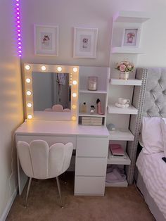 a white vanity with lights on it next to a bed and a desk in a room