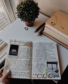 an open book sitting on top of a table next to a potted plant