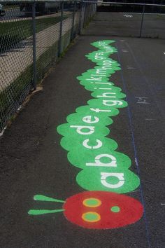 an image of a painted road with words and vegetables on the pavement in front of a chain link fence