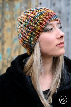 a woman with blonde hair wearing a multicolored knitted hat and black jacket