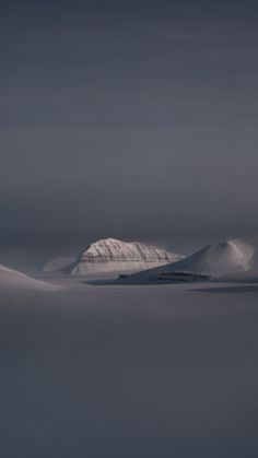 snow covered mountains in the distance under a cloudy sky