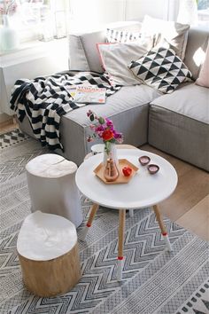 a living room filled with furniture and a white table in front of a gray couch