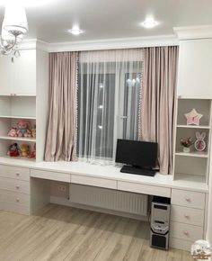 an empty room with white furniture and pink curtains on the windowsill, along with a television