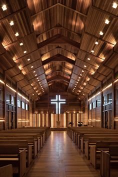 an empty church with wooden pews and a cross hanging from the ceiling above it