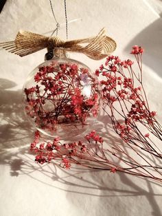 some red flowers are in a clear glass ornament on a white tablecloth