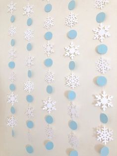 paper snowflakes are hanging from the ceiling in front of a white wall with blue circles