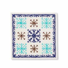 a cross stitch pattern with blue and brown crosses on white fabric, in the shape of snowflakes