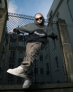 a man in sunglasses and a hoodie is doing a trick on a skateboard