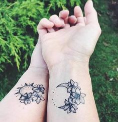 two people with matching tattoos on their arms holding each other's hands in the grass