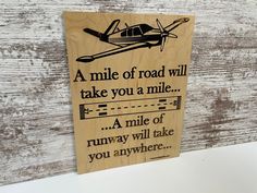 a wooden sign that reads a mile of road will take you a mile, a mile of runway will take you anywhere