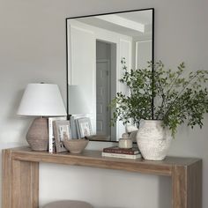 a table with a mirror, lamp and vase on it