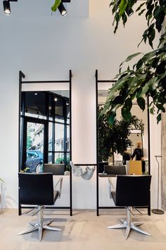 two black chairs sitting next to each other in front of a mirror on the wall