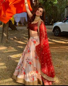 a woman in a red and white lehenga holding up an orange shawl