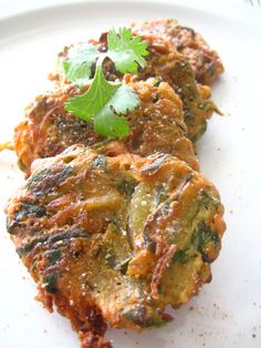 two fritters on a plate with some cilantro and parsley garnish