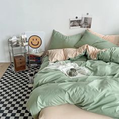 an unmade bed in a bedroom with a smiley face on the wall above it