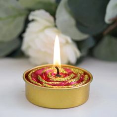 a lit candle sitting on top of a table next to flowers