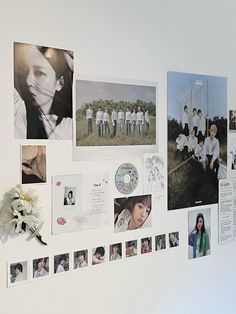 a white wall with many pictures and flowers hanging on it's side, along with other photos