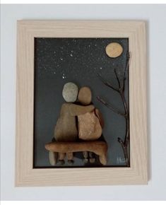 two rocks sitting on top of a wooden bench under a sky filled with stars and moon