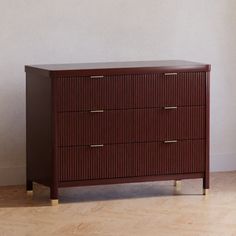 a brown chest of drawers sitting on top of a hard wood floor next to a white wall