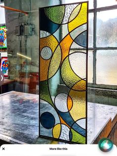 a large stained glass window sitting on top of a wooden table in front of windows