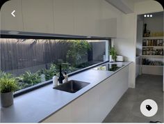 a kitchen with a large window overlooking the yard and garden area, as well as a sink