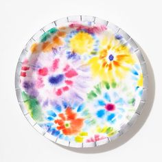 a paper plate with multicolored flowers painted on the outside and inside, sitting on a white surface