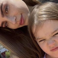 a mother and daughter are posing for a photo together outside in the sun with their hair blowing back