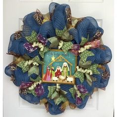 a christmas wreath with the nativity scene hanging on it's front door frame