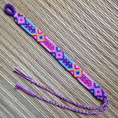 a purple and pink bracelet on top of a wooden table next to a pair of scissors