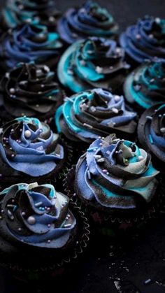 several cupcakes with blue frosting and sprinkles on black background