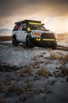 a white truck parked on top of a snow covered field