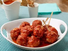 a white bowl filled with meatballs on top of a blue and white table cloth