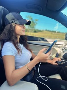 a woman sitting in the driver's seat of a car holding a tablet