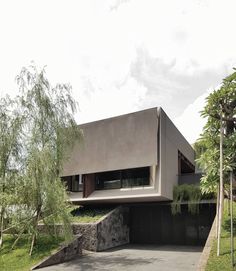 the house is made out of concrete and has trees in front of it on both sides