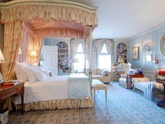 a bedroom with a four poster bed sitting next to a desk and chair in front of a window