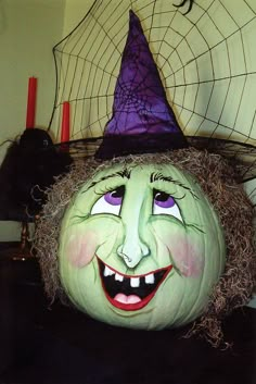 a pumpkin with a witch's hat on top of it, sitting in front of a spider web net