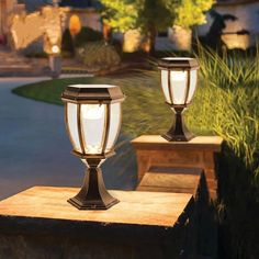 two lights that are sitting on top of a stone block in front of a house